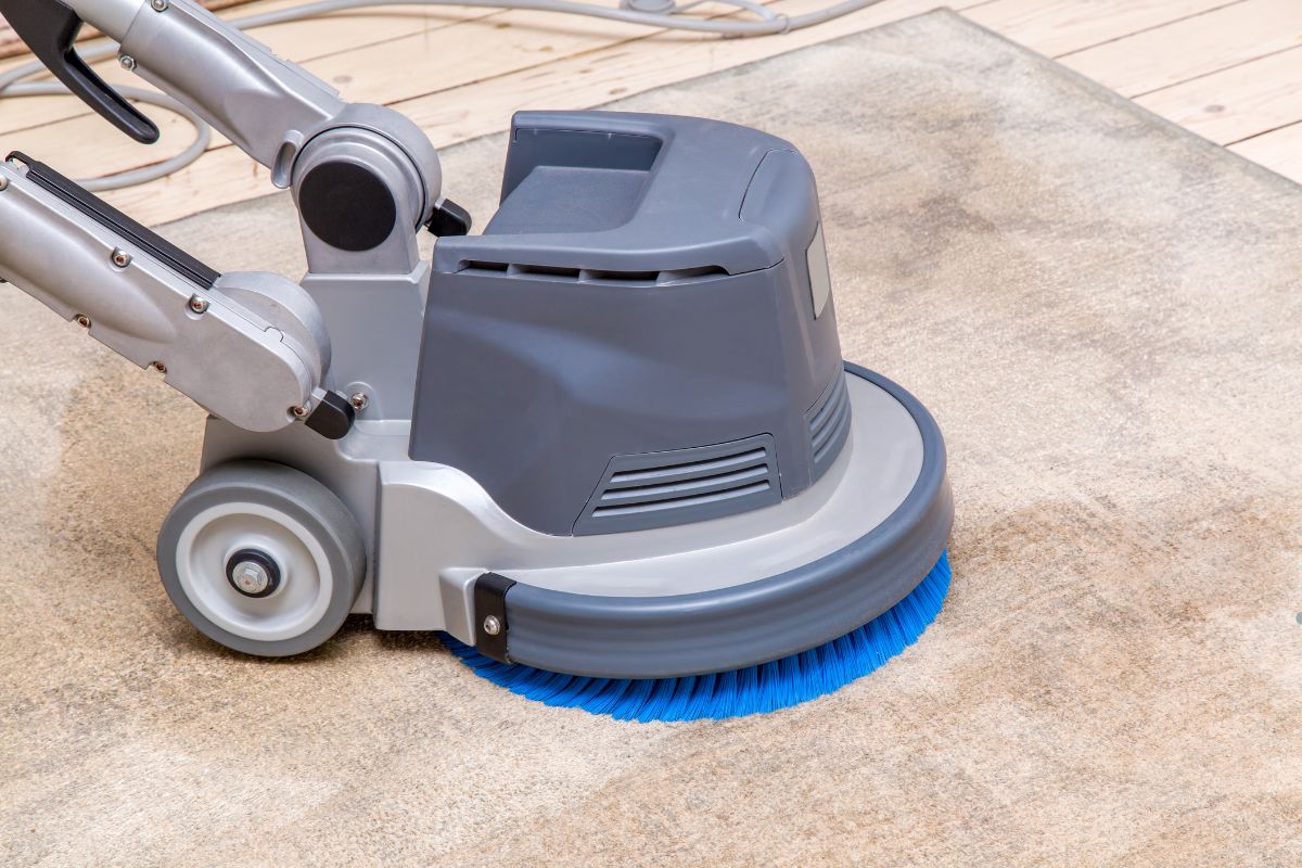 A vacuum cleaner actively cleaning a carpet, representing a professional carpet cleaning service in action.