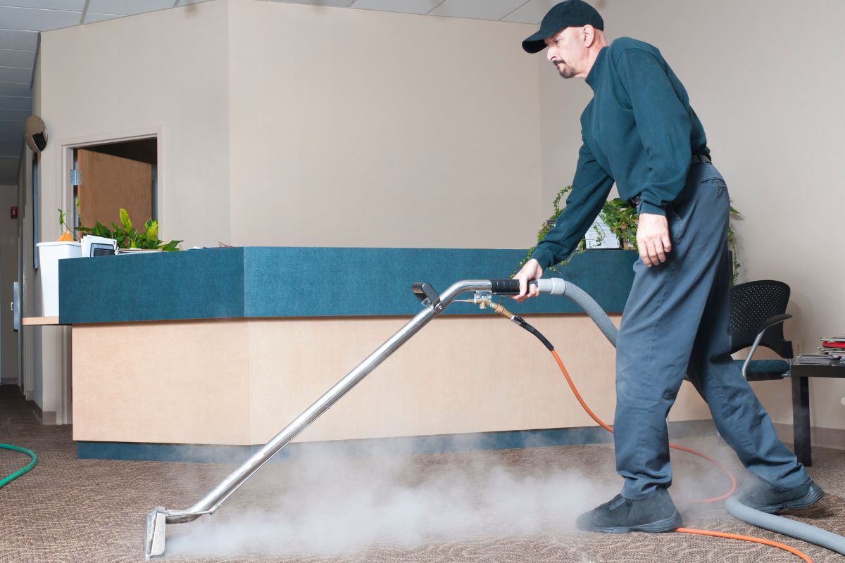 A man operates a vacuum cleaner to remove dirt from a carpet, demonstrating effective carpet cleaning techniques.
