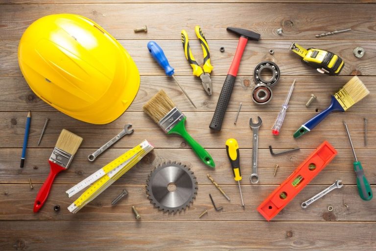 Tools and construction materials scattered across a wooden table, showcasing a work environment.